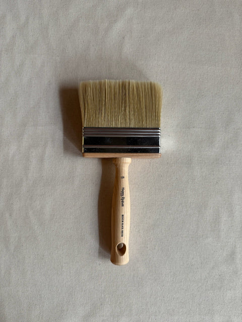 Paint brush with wooden handle on a light gray background